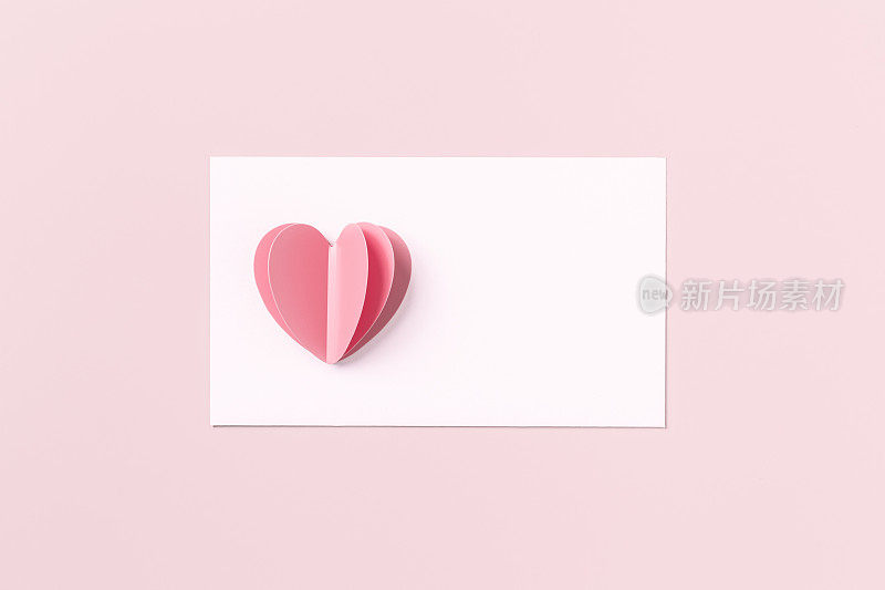Pink cute cut heart and clean white paper for love note on pink colored background. Minimal trend flat lay, pastel color, mock up valentine Day card or wedding invitation. Romantic concept